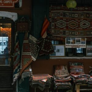 A charming shop with colorful Turkish carpets and rugs displayed outside, with a warm ambiance and intricate textile patterns.