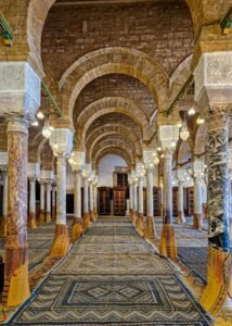 Beautiful interior view of a historic mosque in Tunisia showcasing detailed arches and columns.